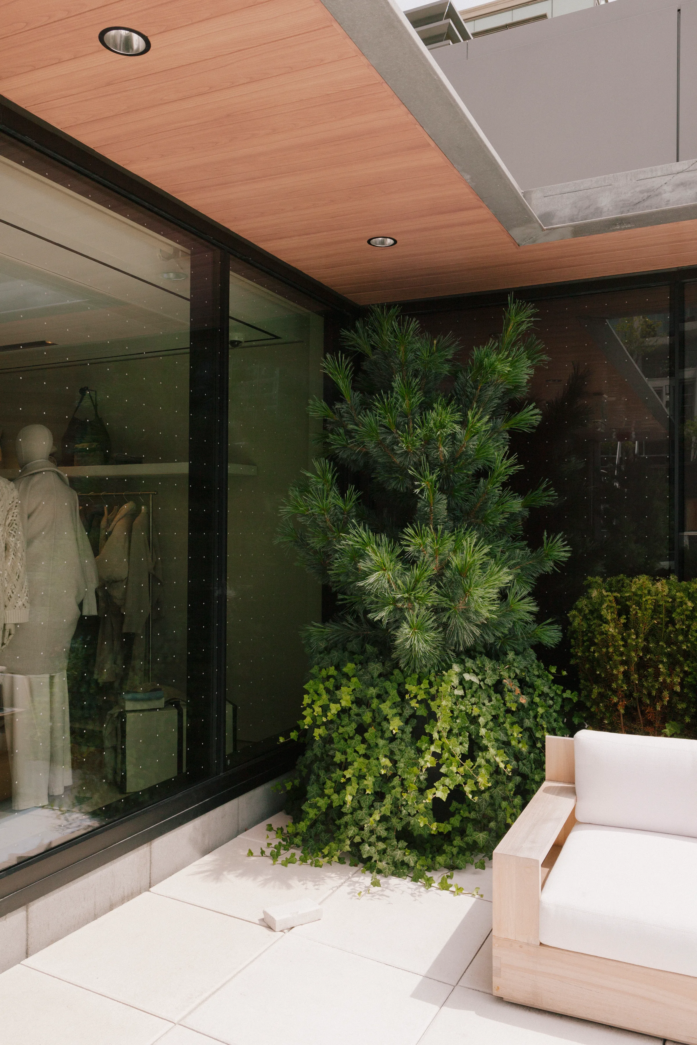 Rooftop garden with cedar hedges, white outdoor furniture and city views at Brunello Cucinelli