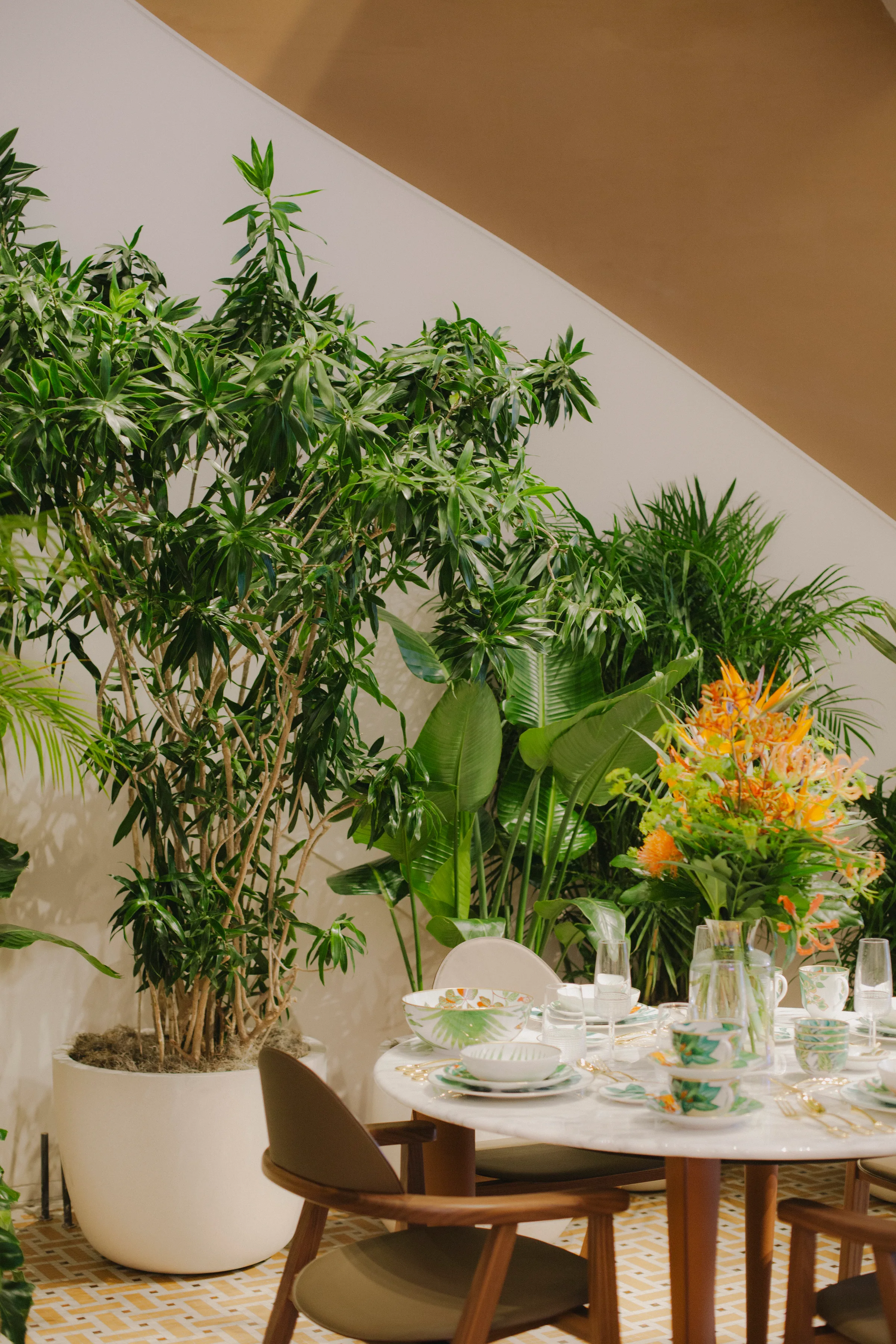 Tropical dining vignette with Areca palm, Schefflera and orange Heliconia at Hermès Yorkville