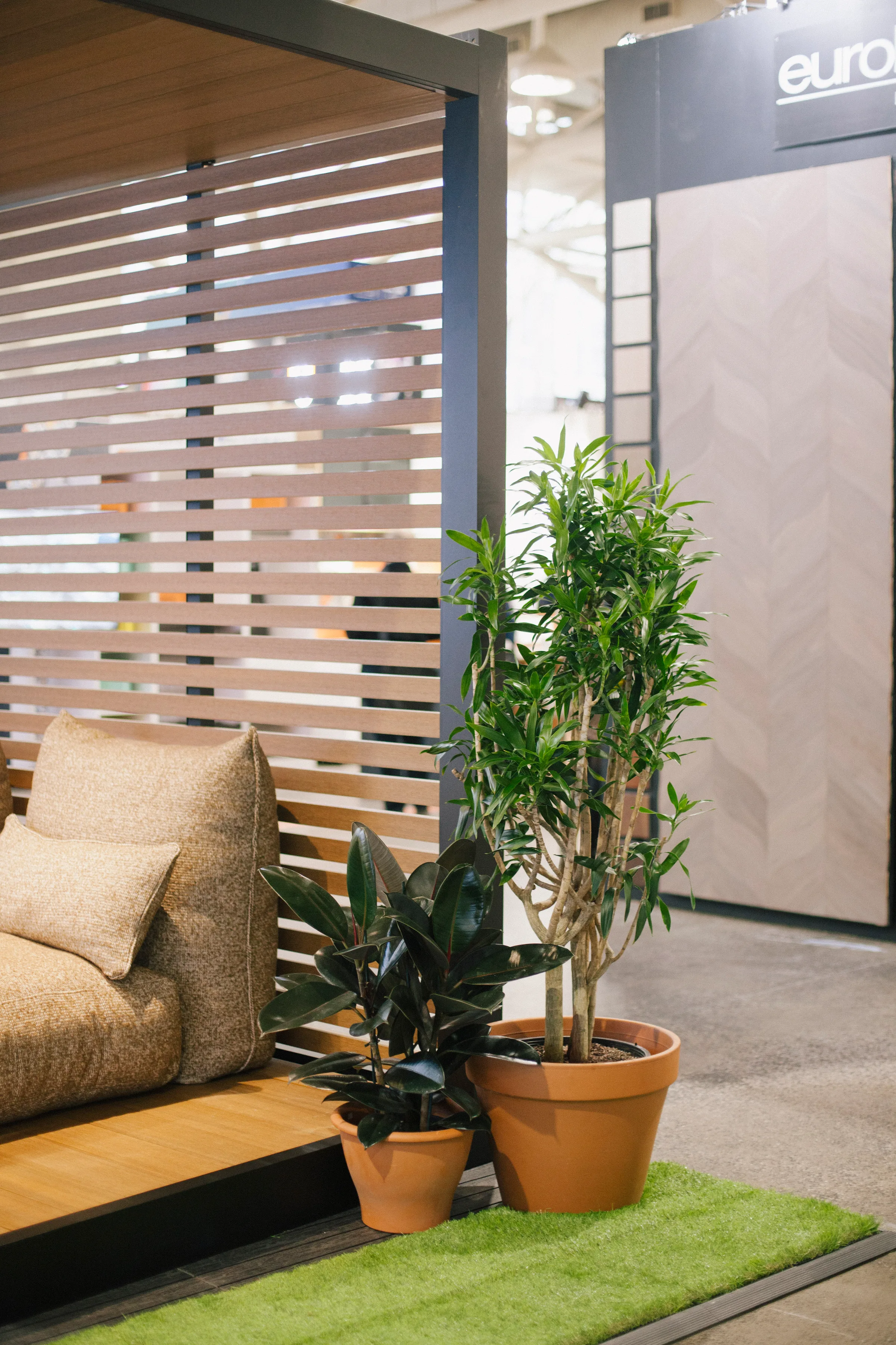 Cozy seating area with Ficus tree and Rubber Plant in slatted wood booth at Interior Design Show