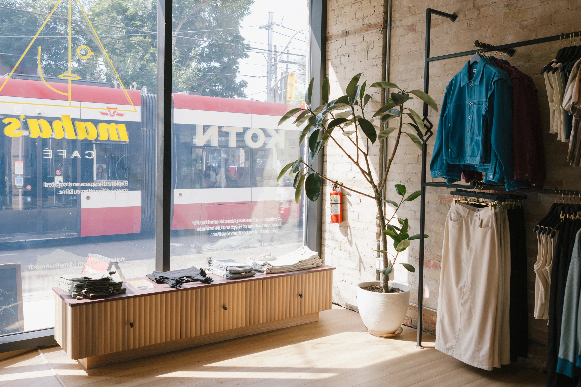 Storefront view with streetcar passing and KOTN branding with Rubber Tree in window