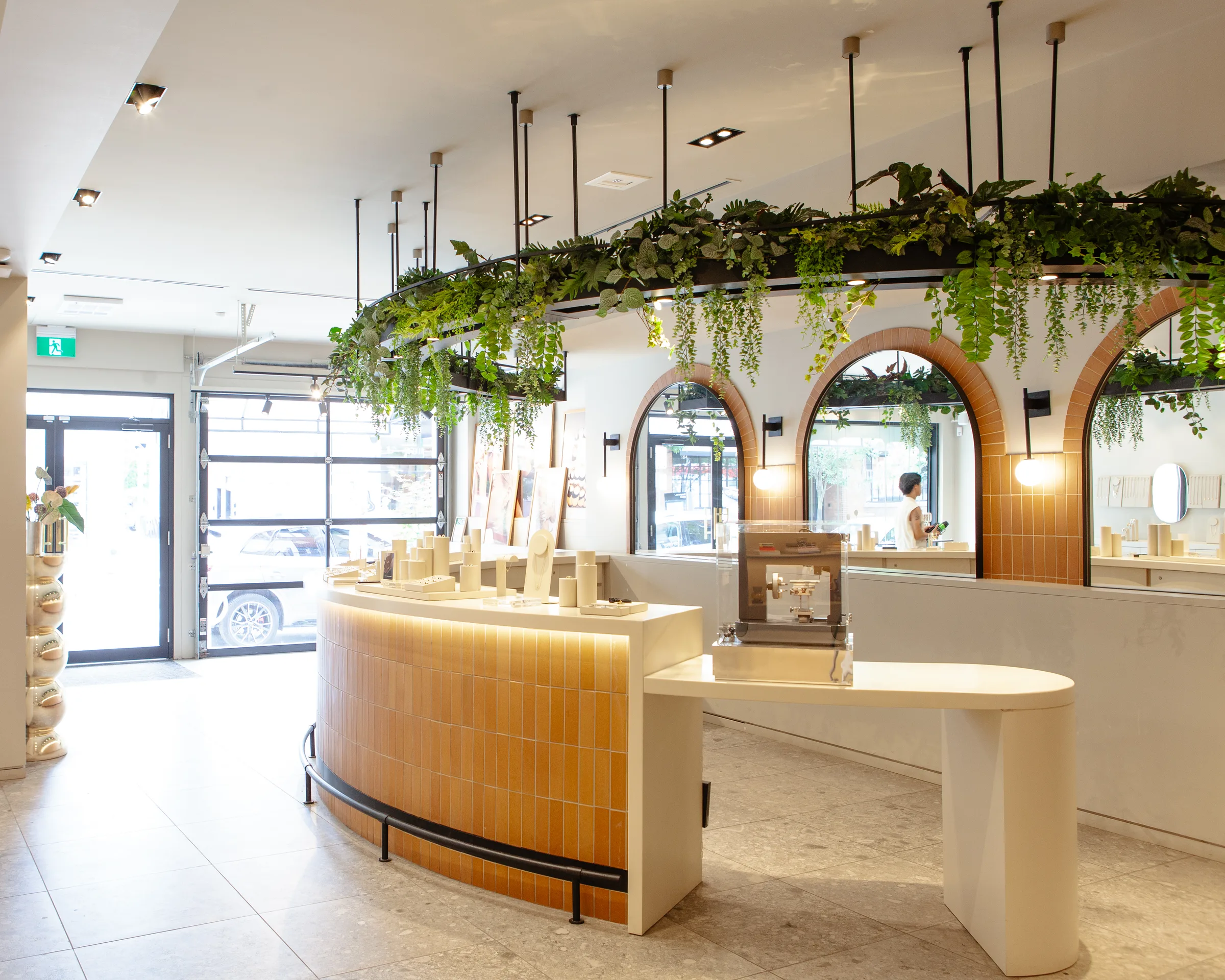 Entrance view of Mejuri store with curved counter and hanging greenery installation