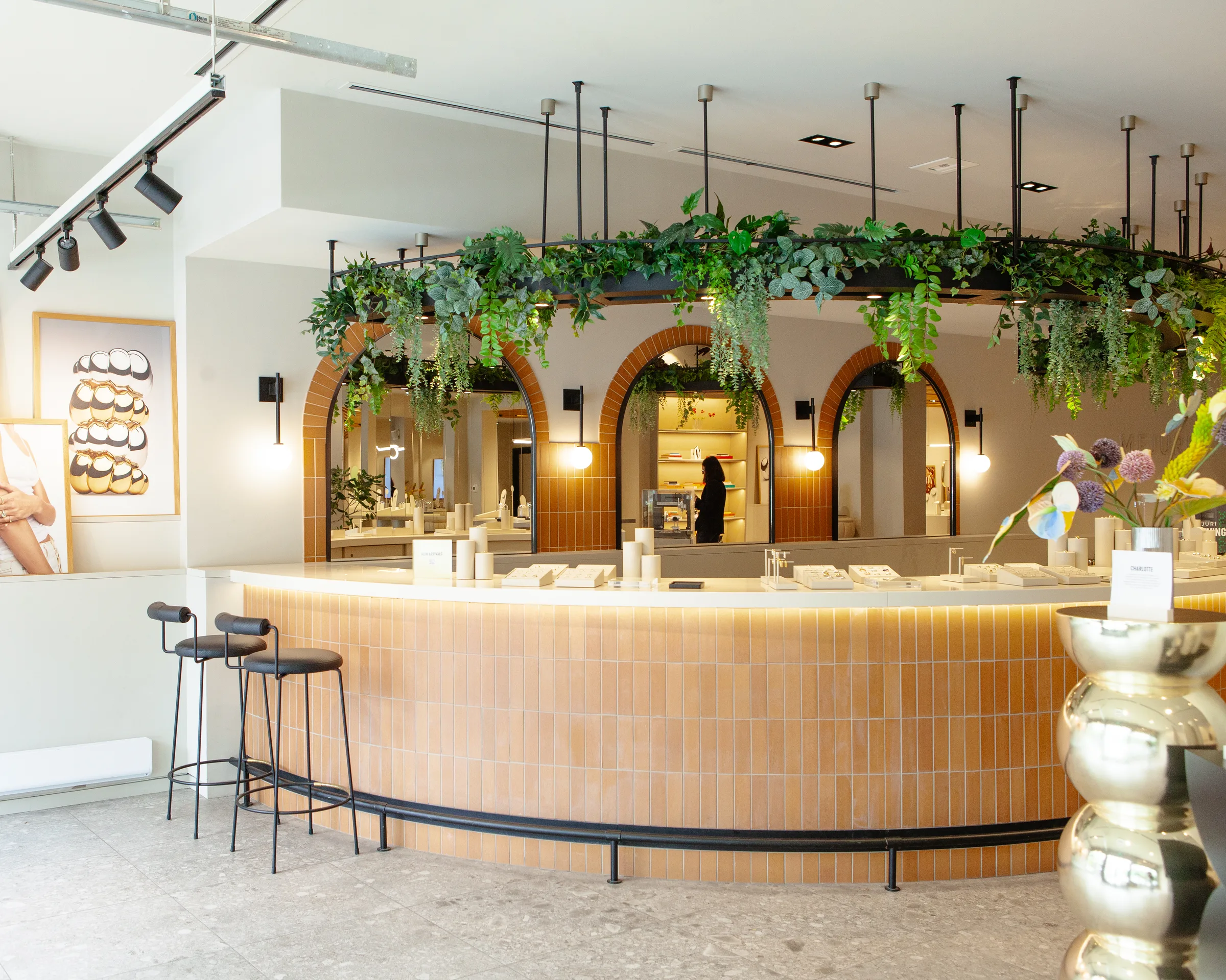 Counter seating area with hanging plants and arched mirrors at Mejuri jewelry store