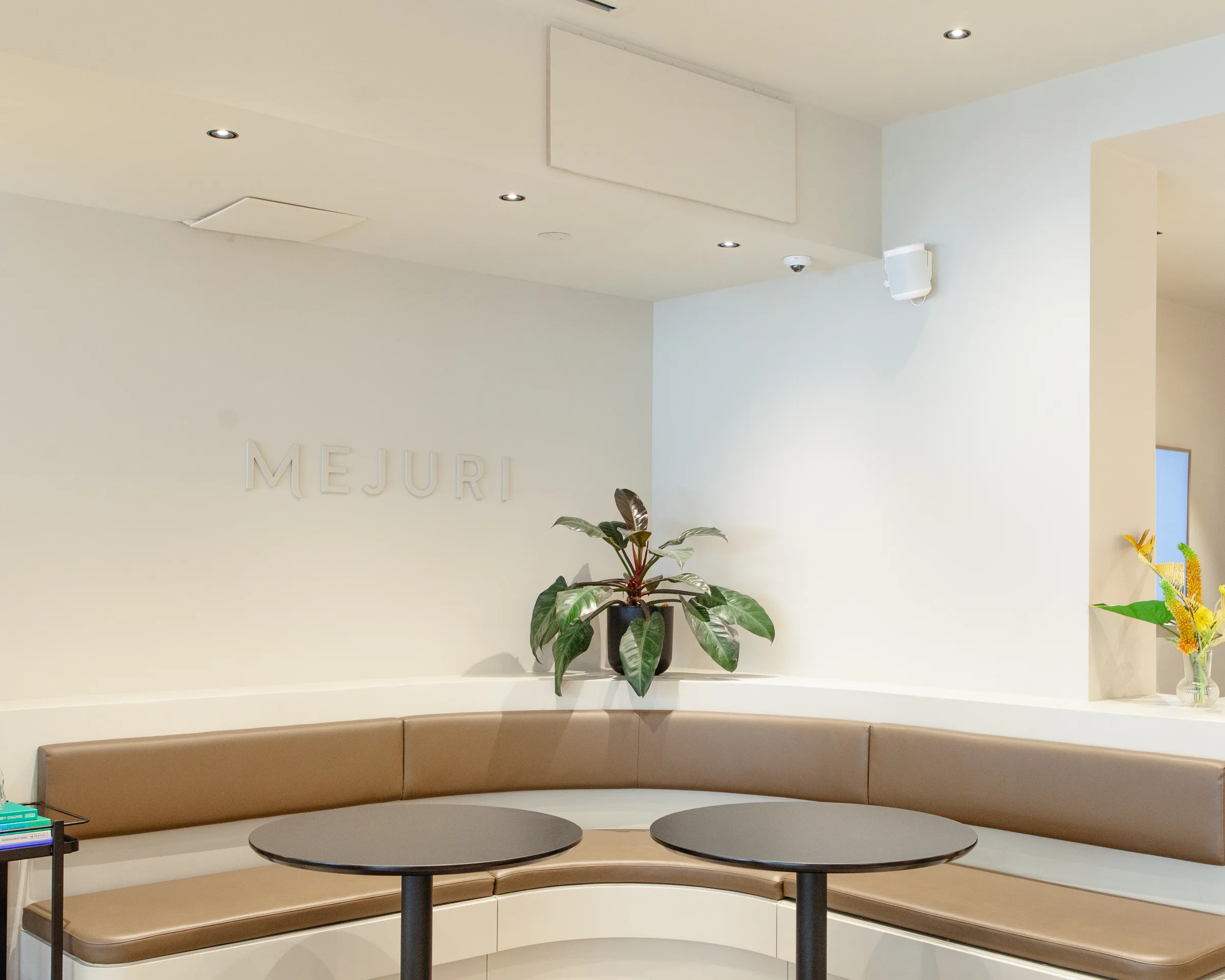 Seating nook with Mejuri branding and tropical plant accent