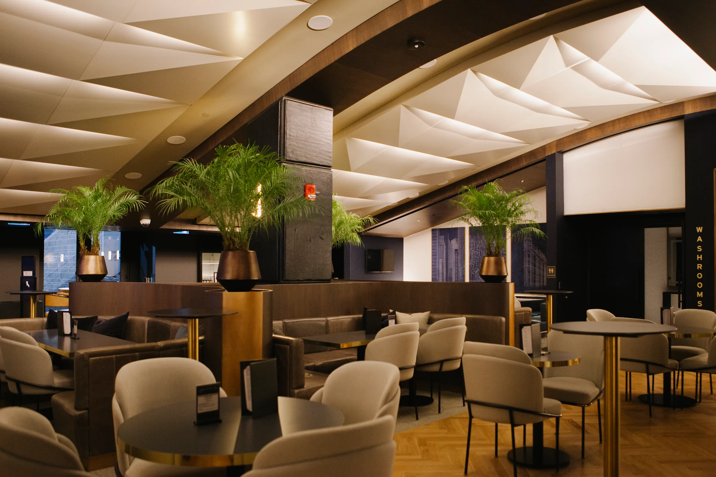 VIP lounge with Areca Palms in bronze planters and geometric ceiling at Rogers Centre